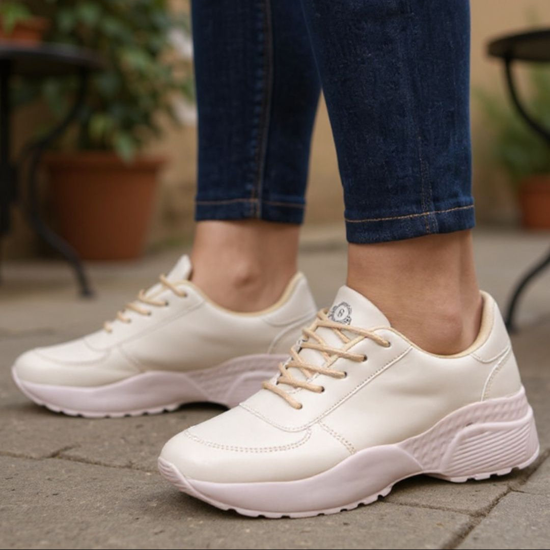 White sneakers worn with blue jeans on a pavement background