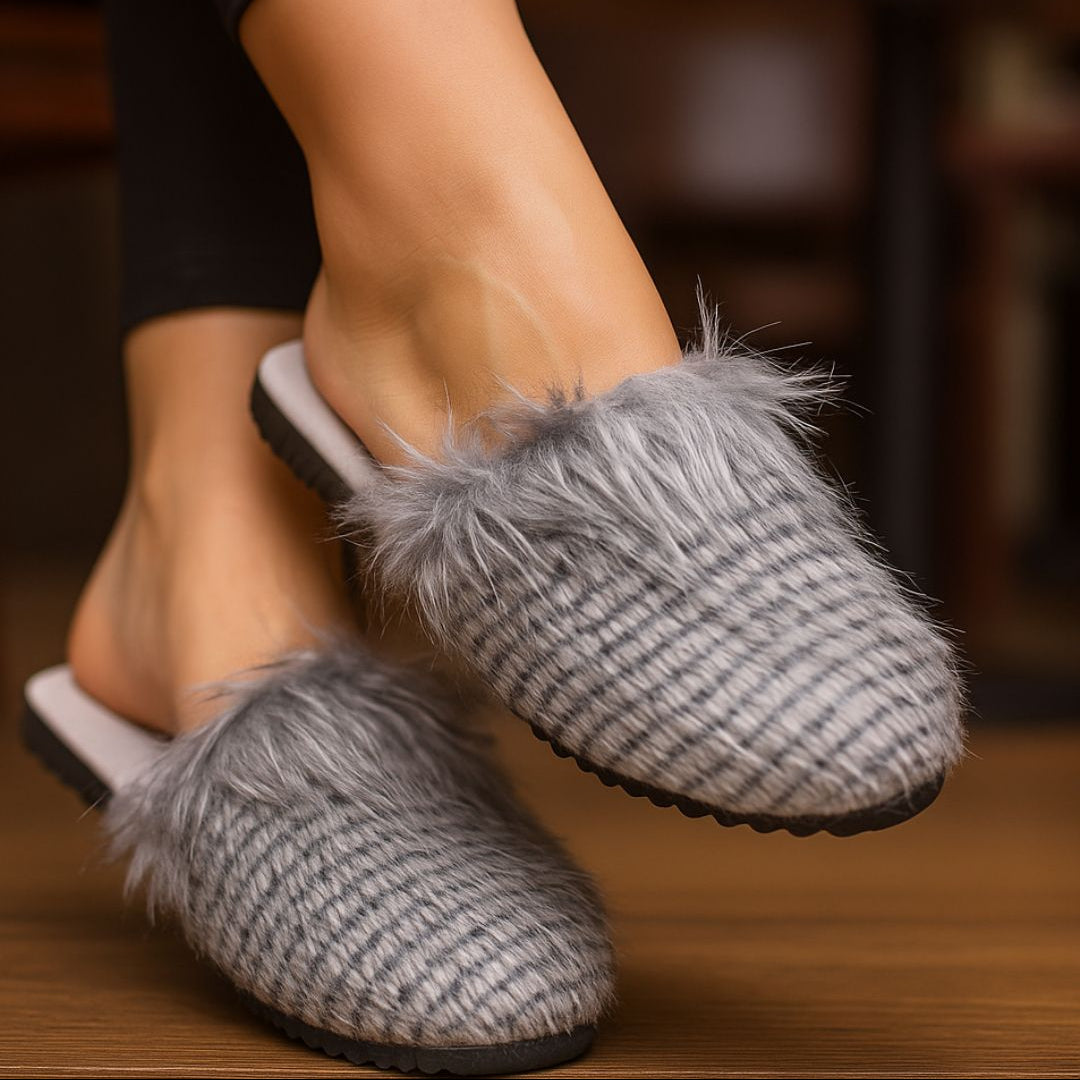 Gray slippers with fluffy fur trim worn by a person indoors.