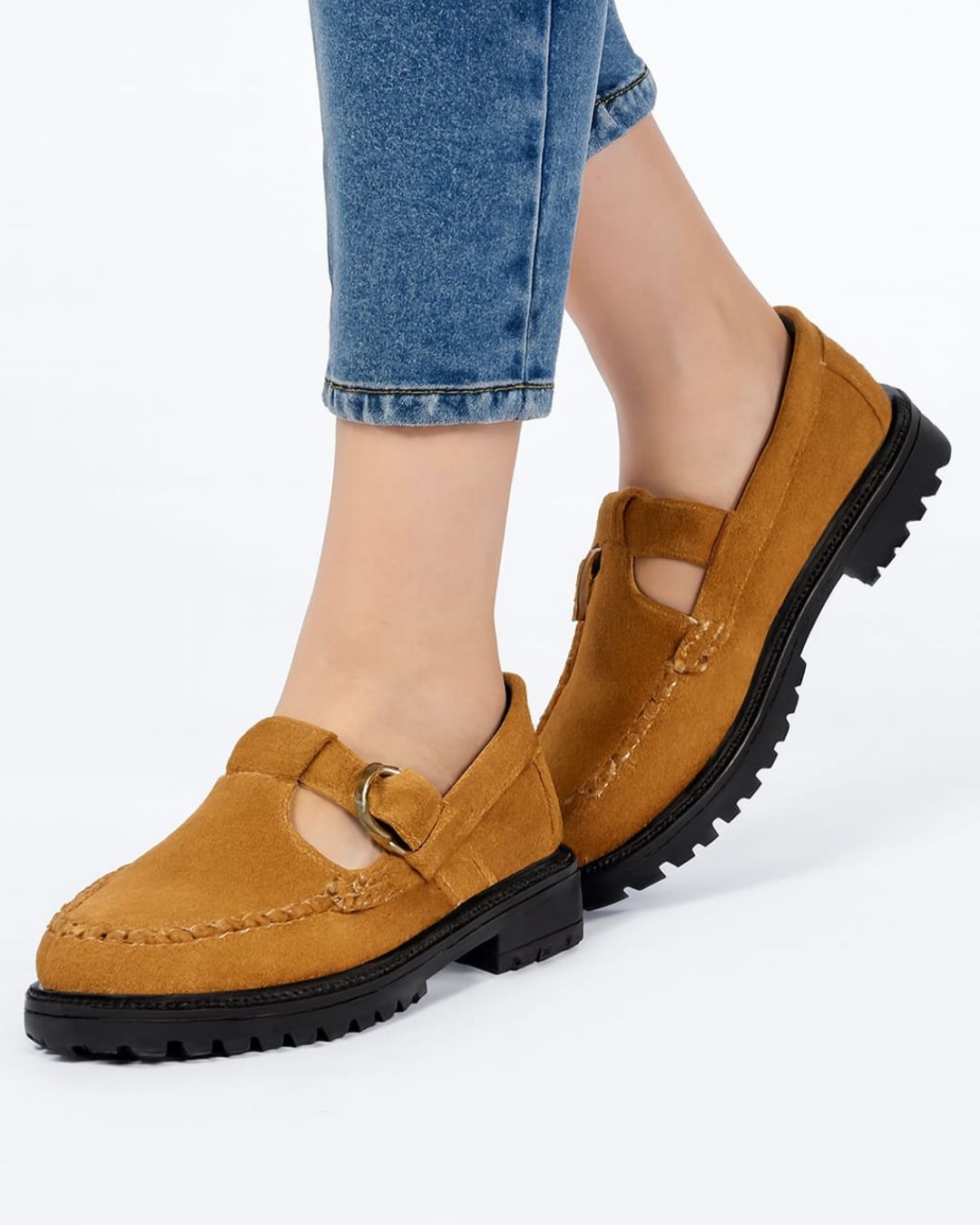 Brown loafers worn with blue jeans on a white background