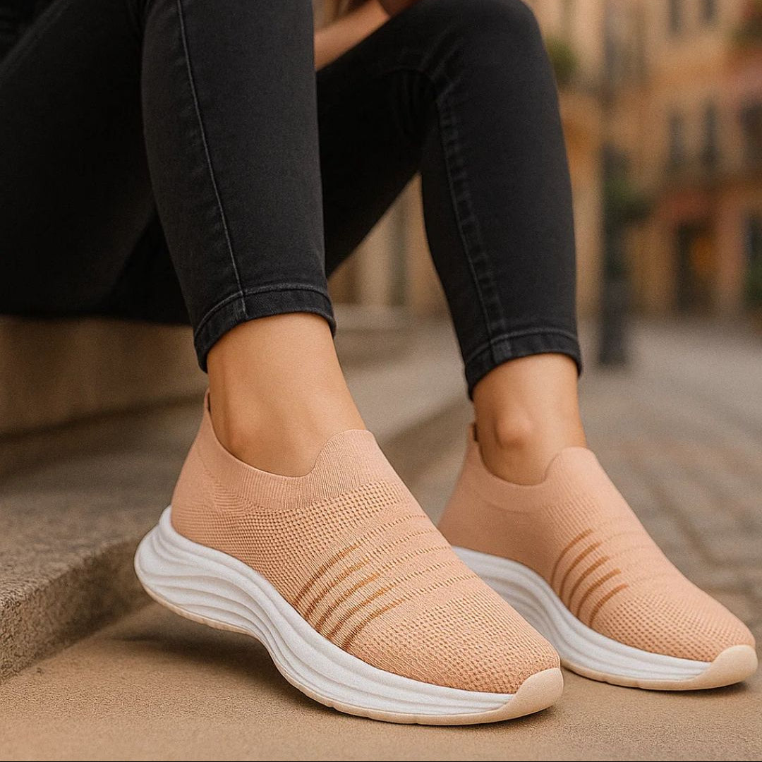 Person wearing beige slip-on shoes with white soles on a blurred street background
