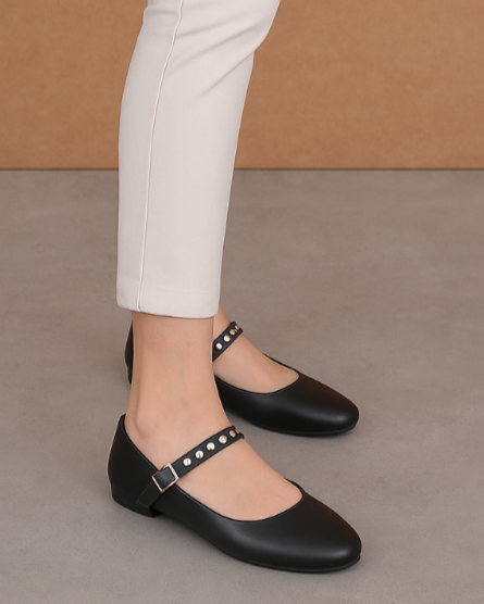 Person wearing white pants and black shoes against a brown background