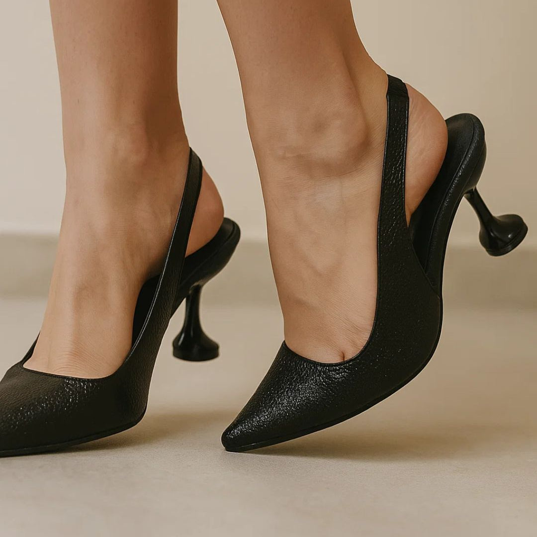 Black high-heeled shoes worn by a person on a neutral background