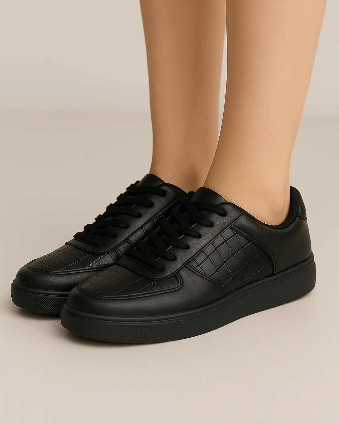 Black sneakers worn by a person on a beige background