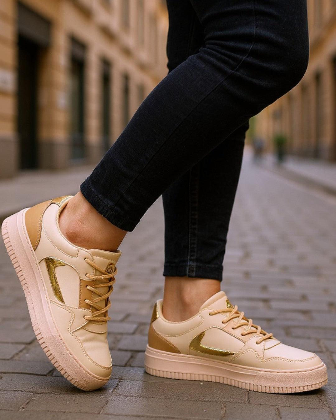 Beige sneakers with gold accents worn on a street.