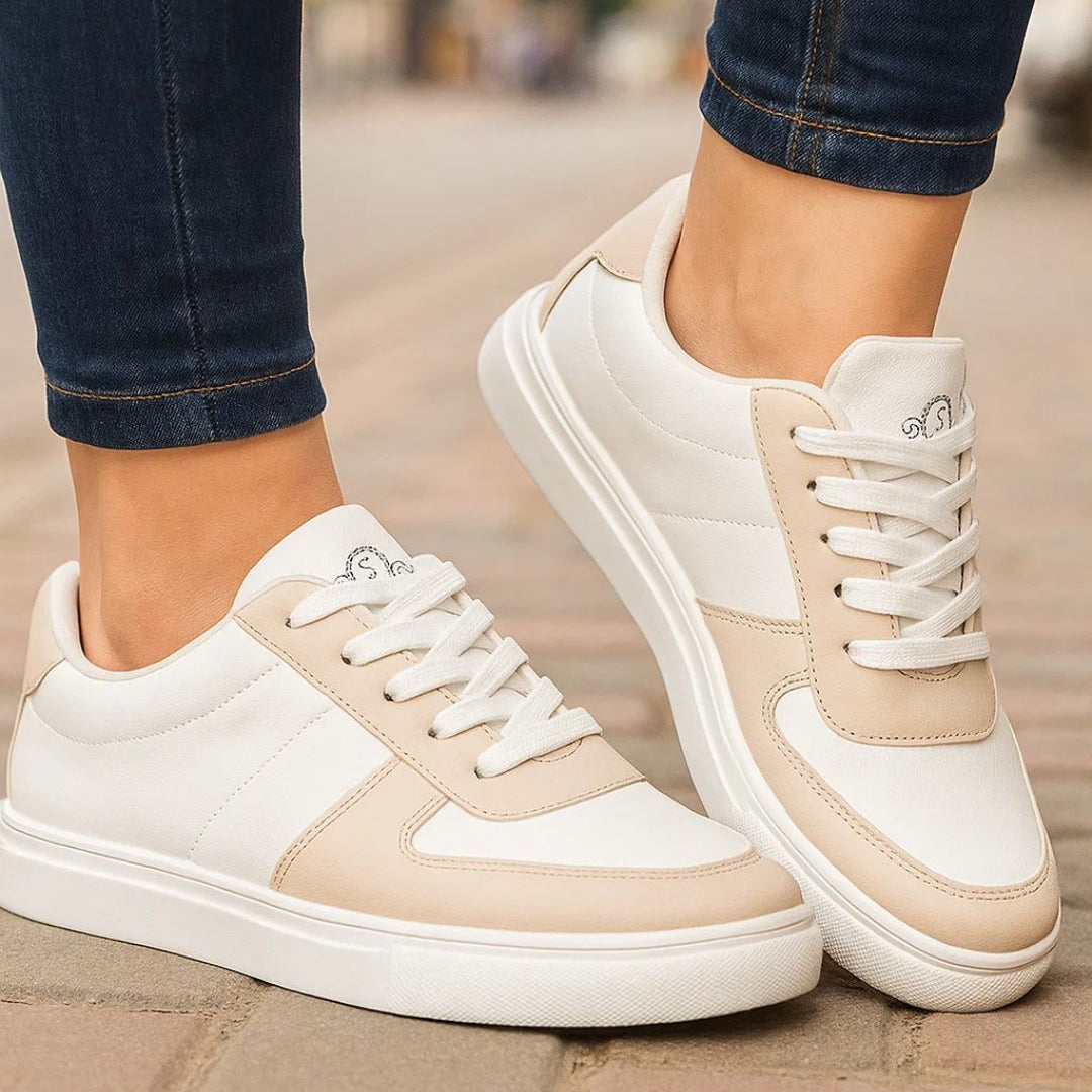 White and beige sneakers worn on a blurred street background