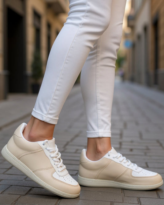 Person wearing beige sneakers and white pants on a city street.