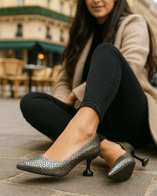 Woman wearing silver high heels with a leopard print pattern on a stone pavement.