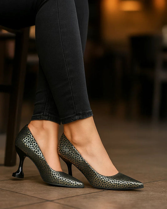 Woman wearing black high-heeled shoes with a patterned sole in an indoor setting.
