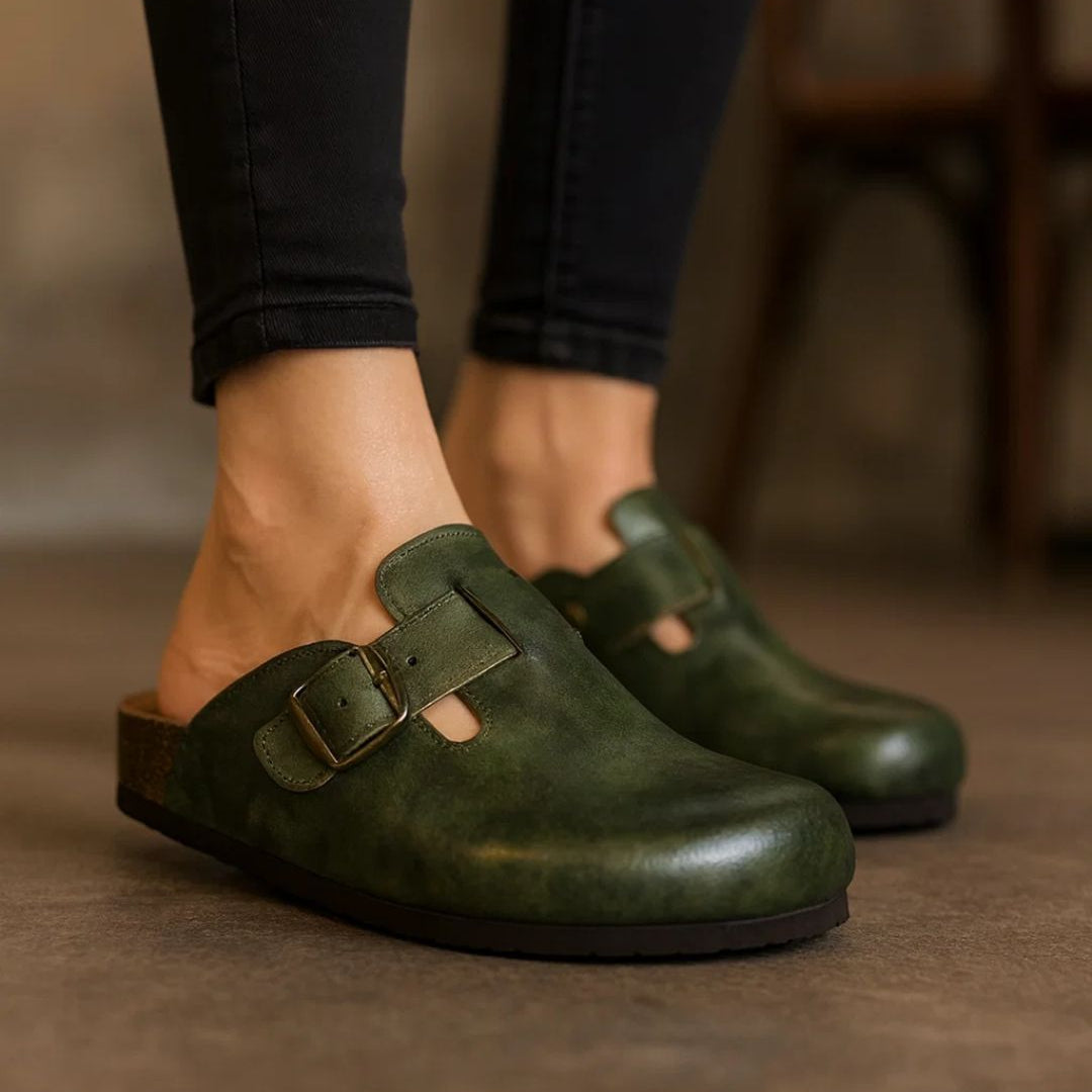 Green clogs worn with black pants on a blurred background