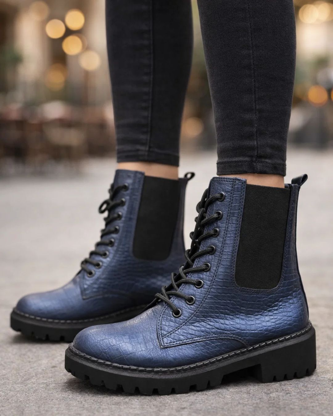 Blue leather boots with black soles worn by a person on a blurred background