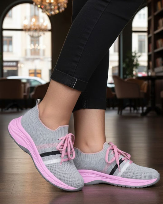 Gray and pink sneakers worn indoors with blurred background