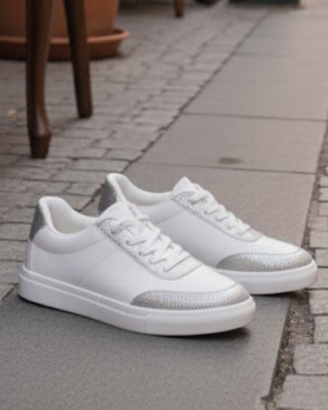 White sneakers with metallic accents on a pavement background
