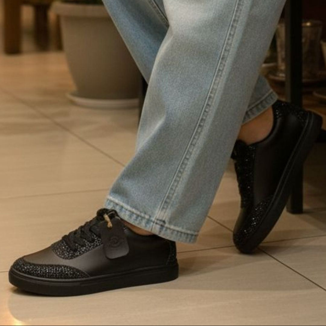 Person wearing black shoes and light blue jeans on a tiled floor.