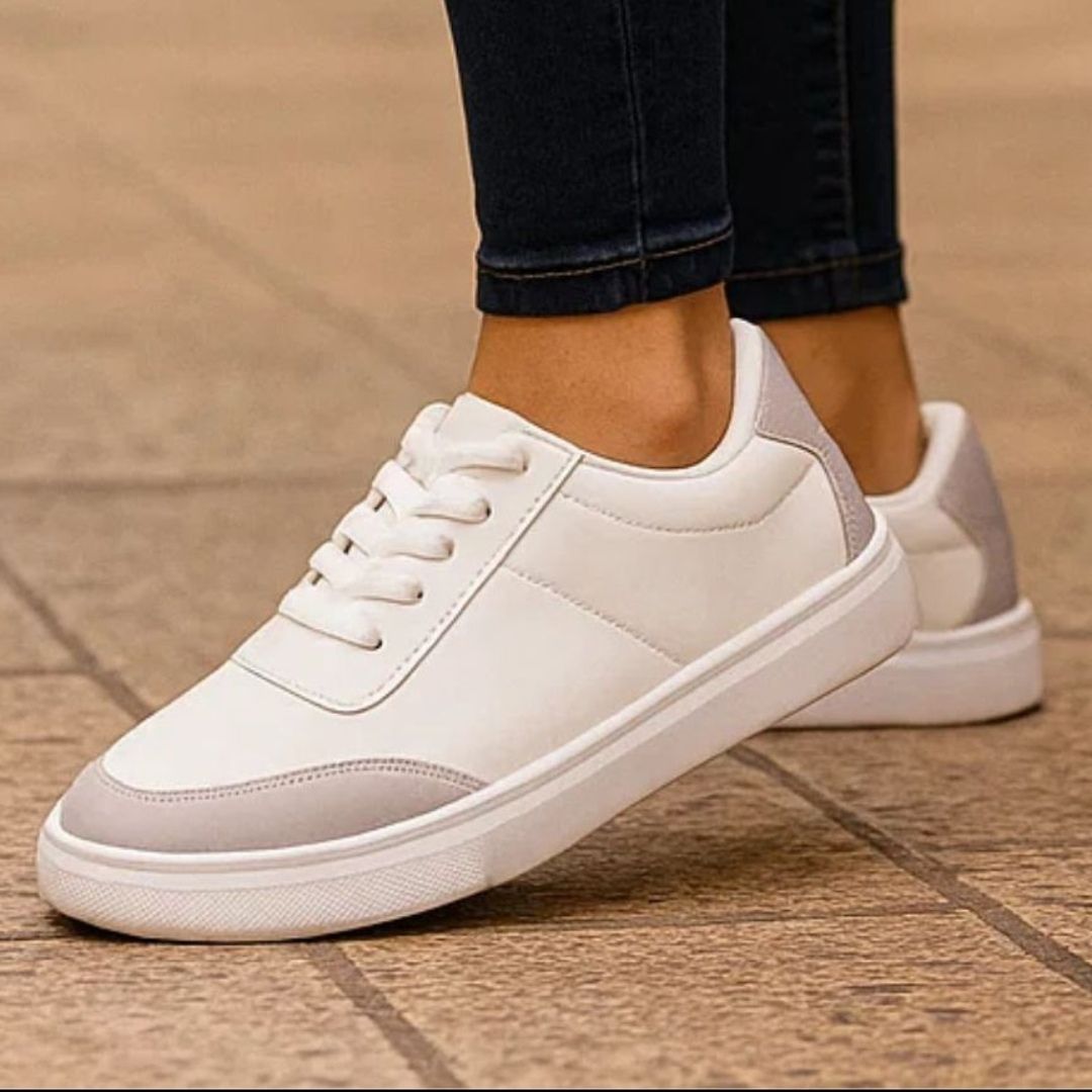 White sneakers worn with dark jeans on a wooden floor