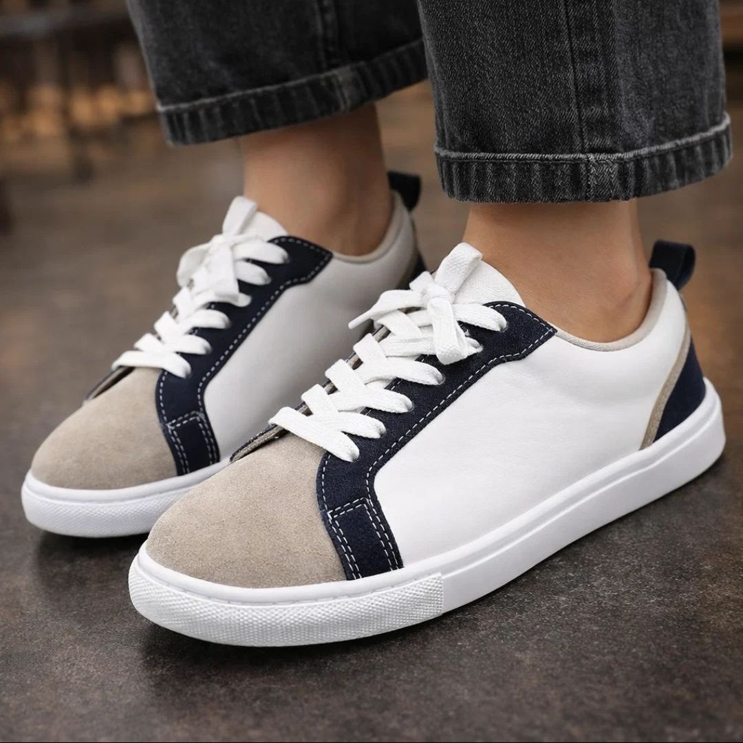 White and beige sneakers with navy accents worn by a person.