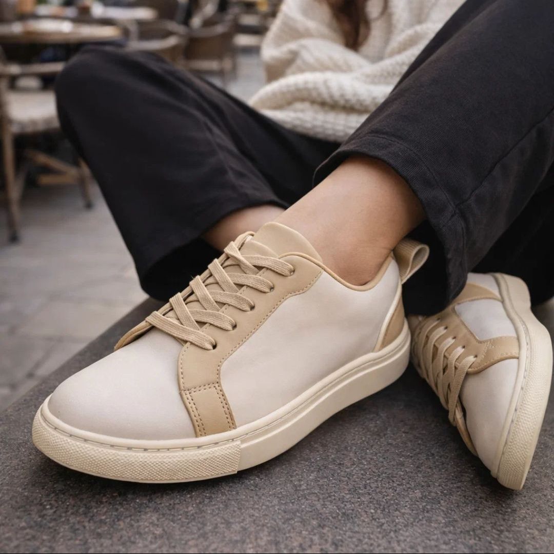 White and beige sneakers worn by a person sitting on a bench.