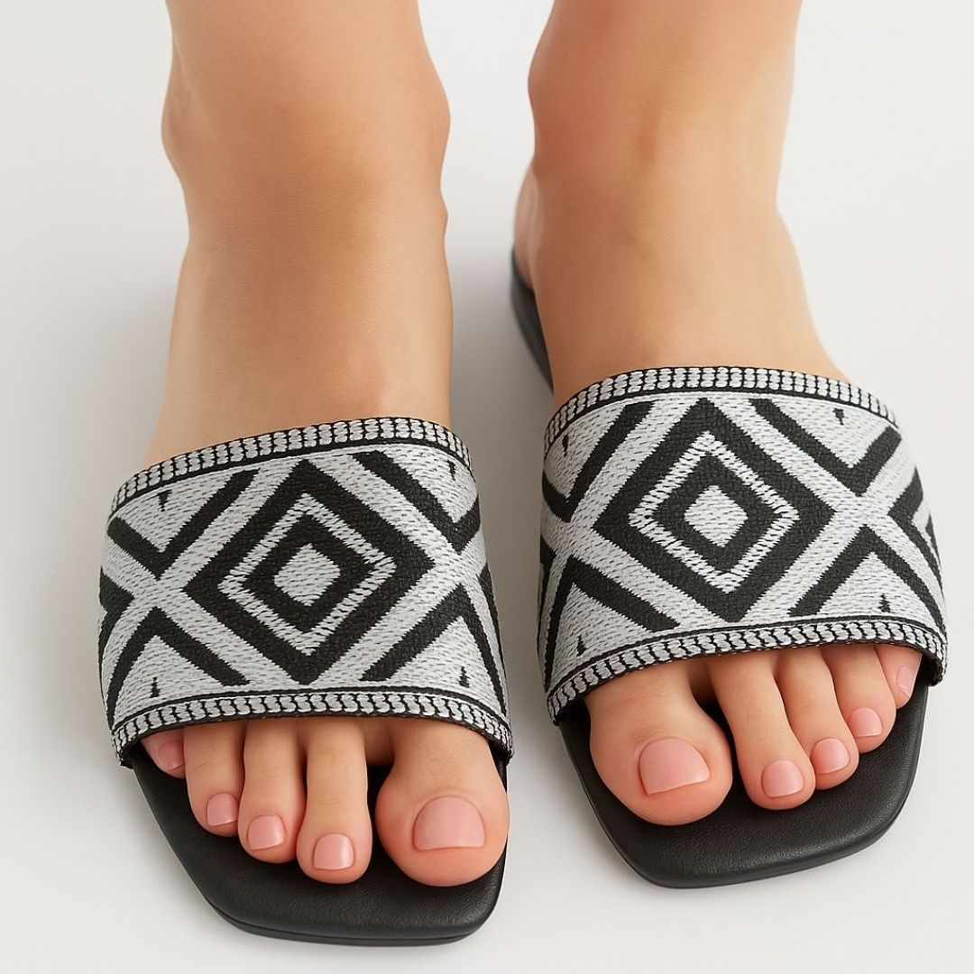 Black and white patterned sandals on feet against a light background