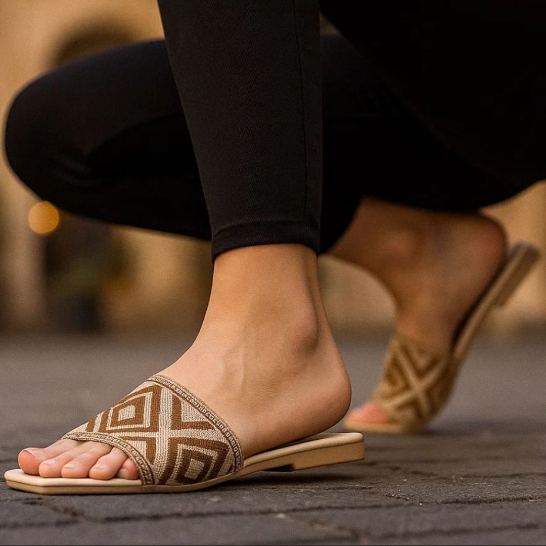 Close-up of feet wearing brown sandals with geometric patterns on a blurred background