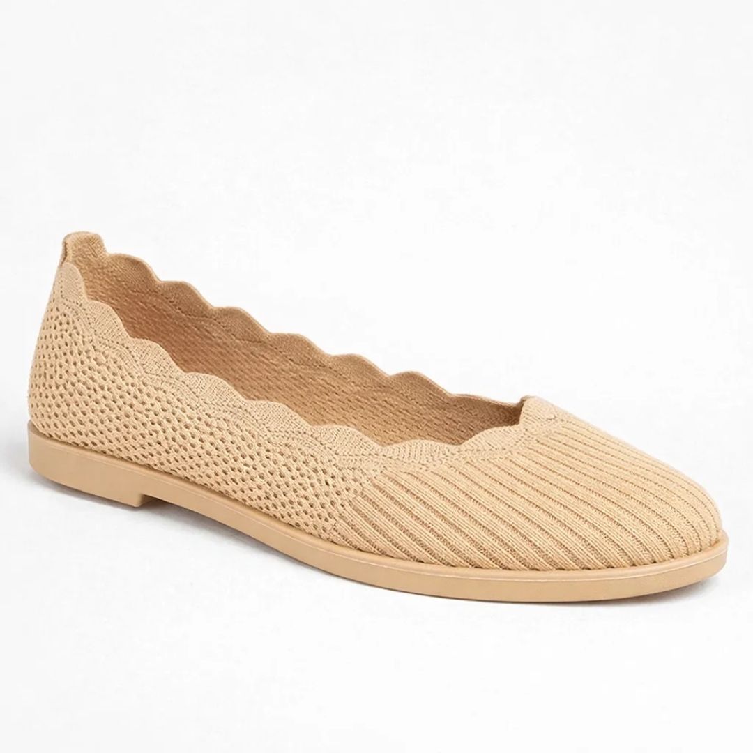 Beige flat shoe with textured sole on a white background