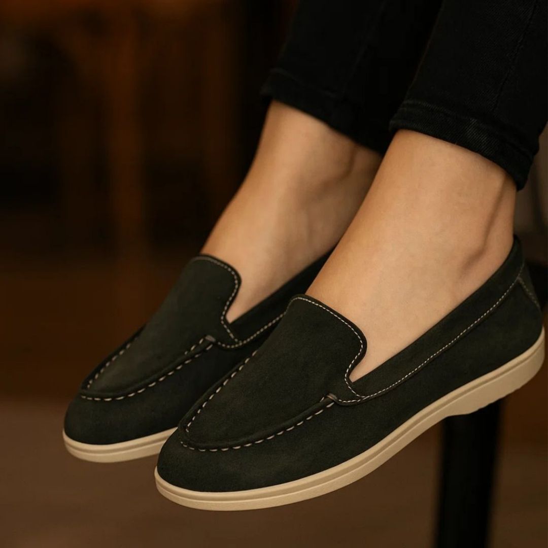 Black loafers worn with black pants on a blurred background