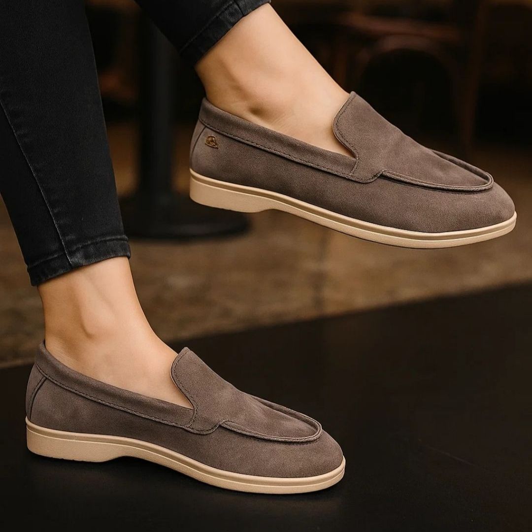 Brown loafers worn with dark jeans on a blurred background