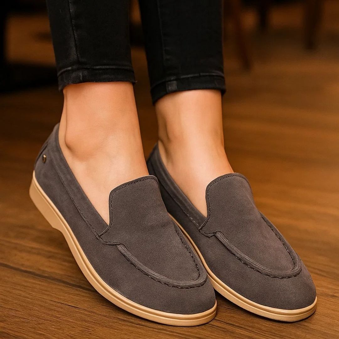 Brown loafers worn with black jeans on a wooden floor