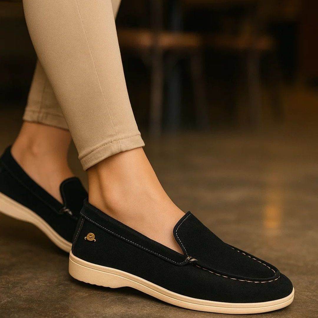 Black loafers worn with beige pants on a blurred background