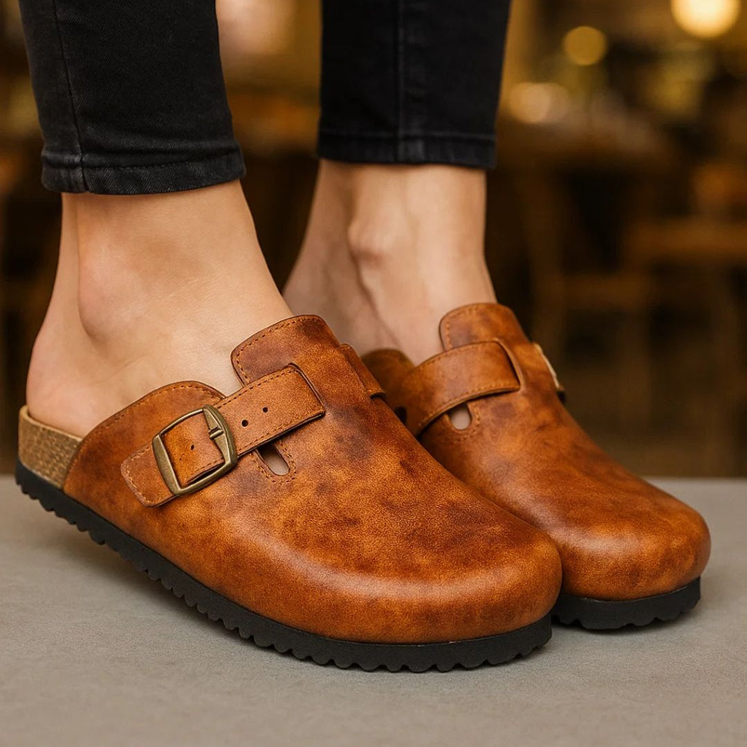 Brown leather shoes with buckles worn by a person on a blurred background