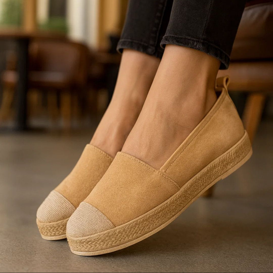 Tan espadrille shoes worn with black jeans in an indoor setting