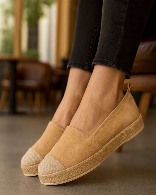Tan espadrille shoes worn with black jeans in an indoor setting