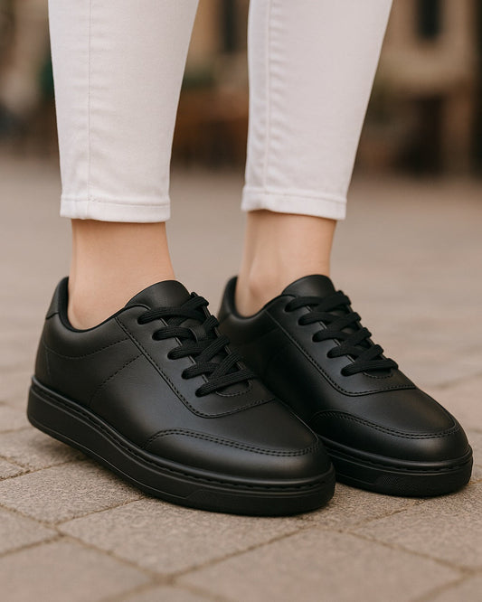 Black sneakers worn with white pants on a blurred outdoor background
