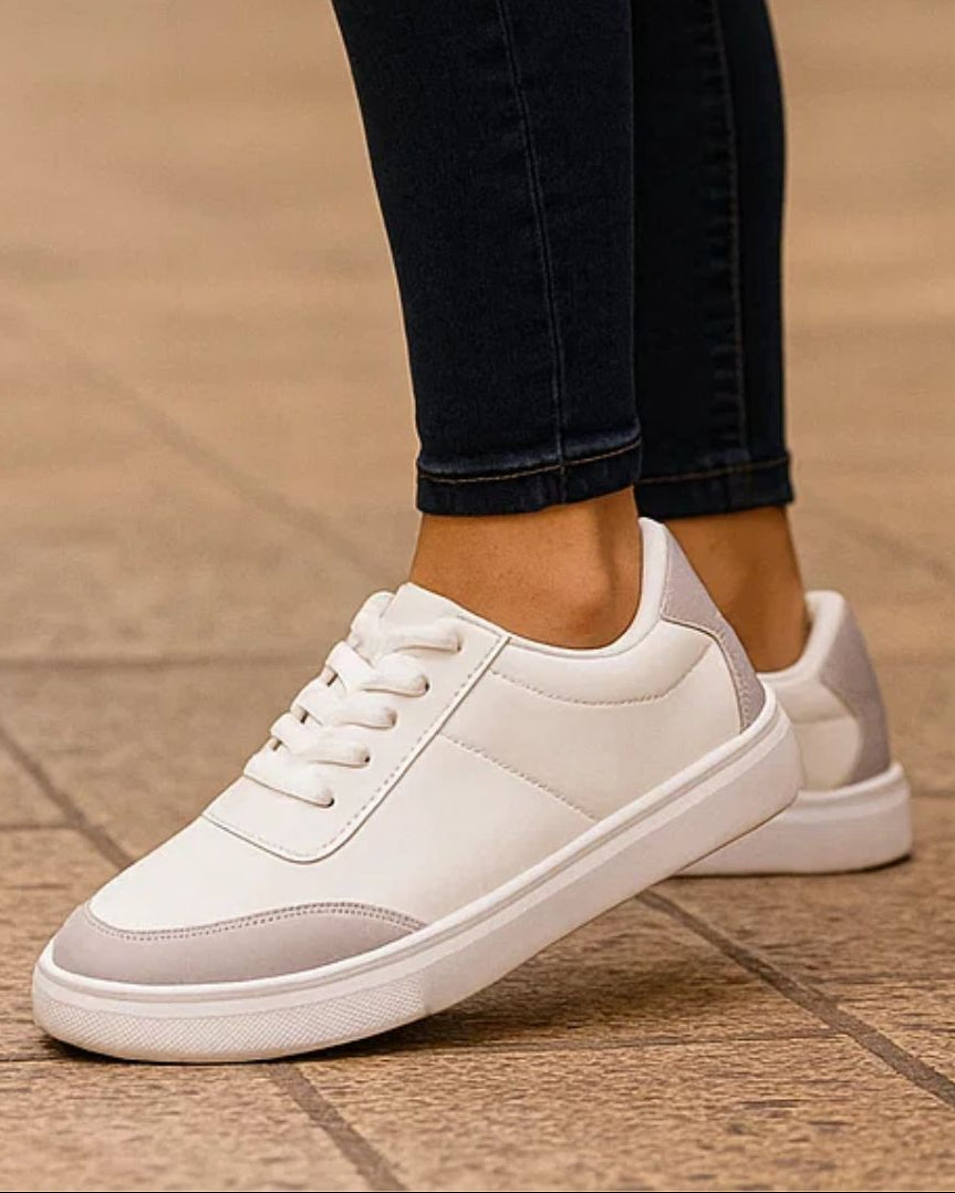 White sneakers with gray accents worn on a tiled floor