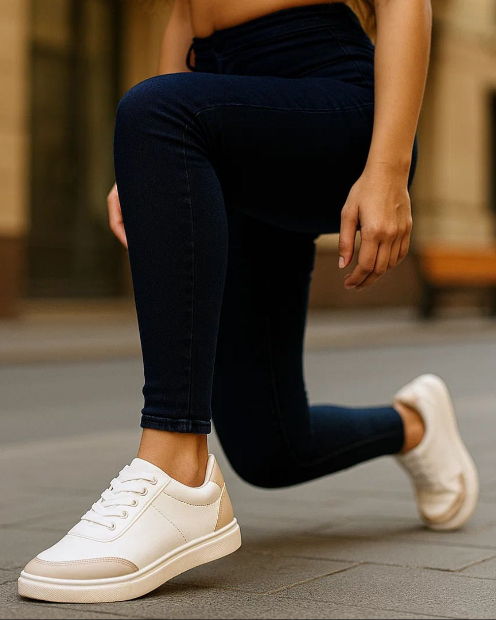 Person wearing white sneakers and dark jeans on a blurred street background