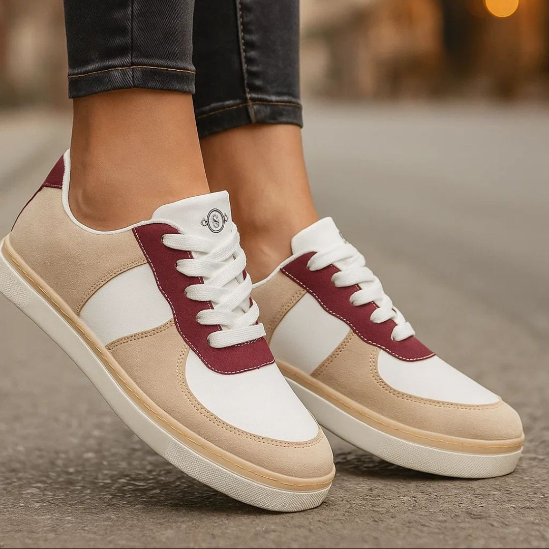 Beige, white, and maroon sneakers worn with dark jeans on a blurred street background