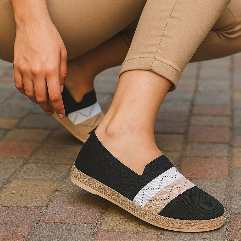 Person wearing beige pants and black and white shoes on a paved surface