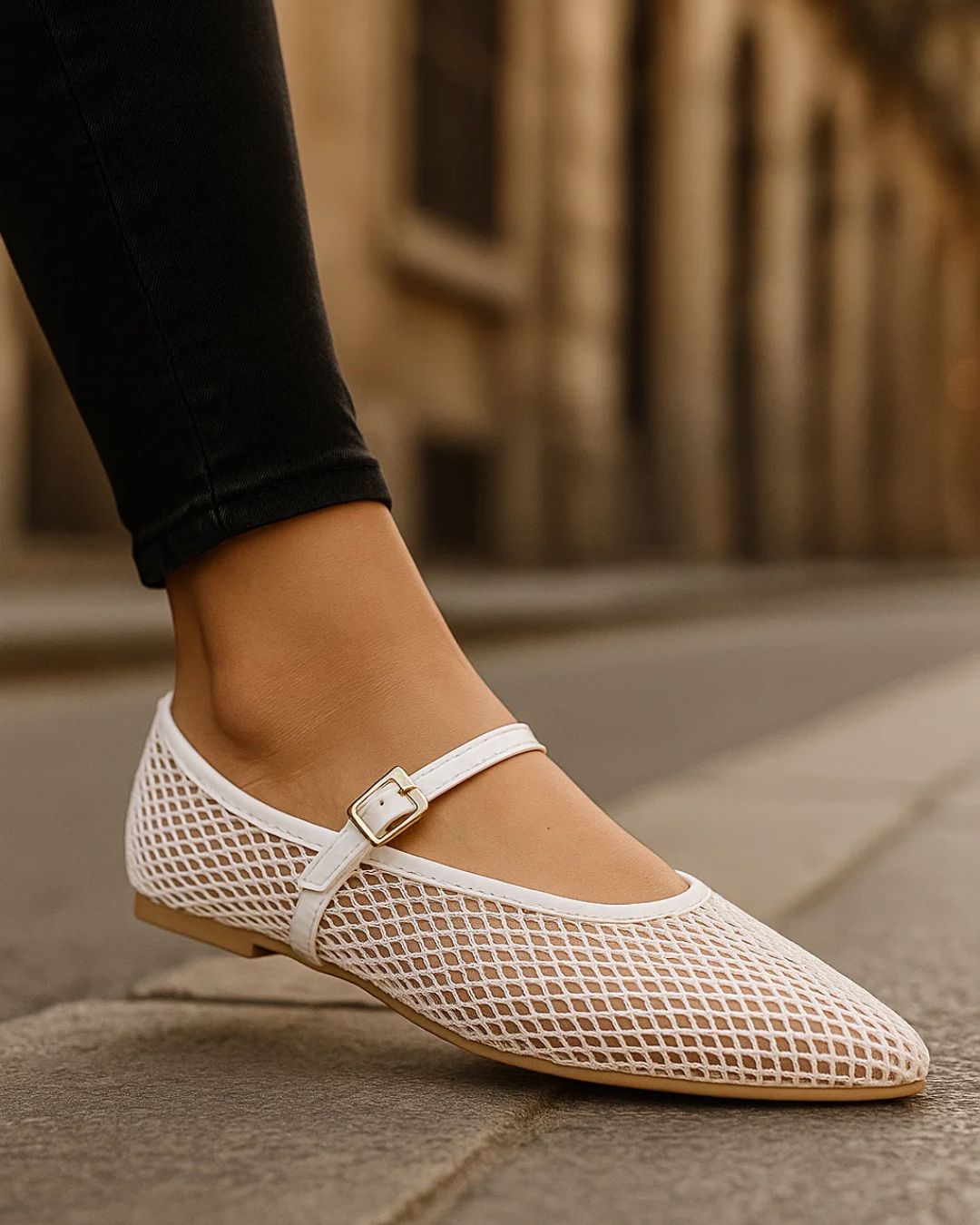 White mesh flat shoe worn on a blurred outdoor background