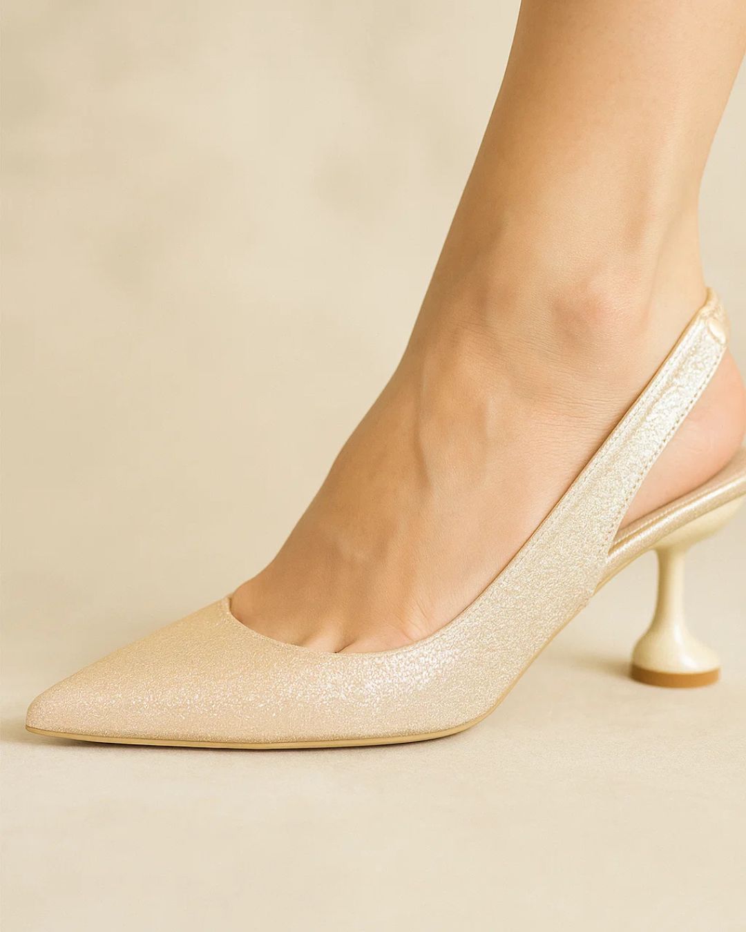 Gold glitter high-heeled shoes on a neutral background