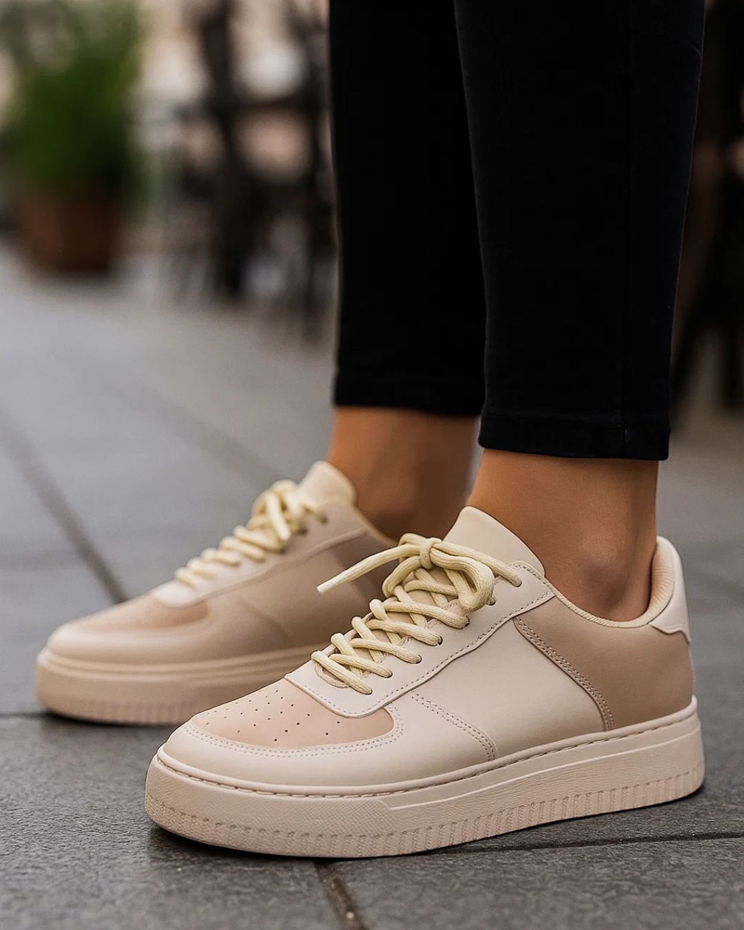 Beige sneakers worn on a blurred outdoor background