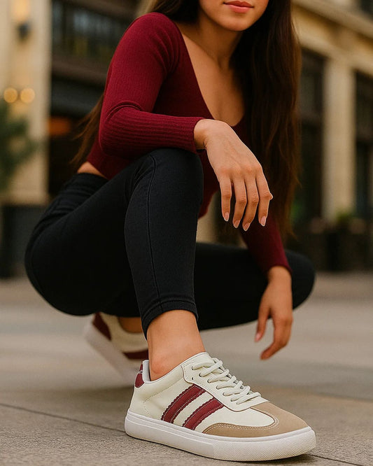 Person wearing a maroon long-sleeve top and black pants with white and brown sneakers.