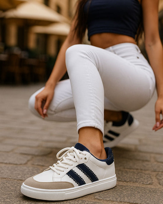 Person wearing white sneakers with navy stripes on a blurred street background