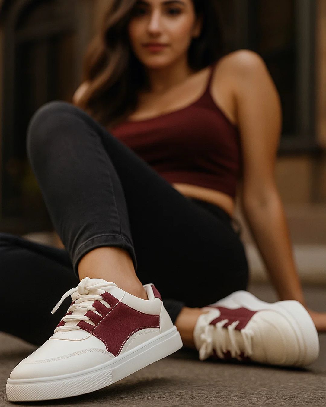 Person wearing maroon and white sneakers sitting on a surface.