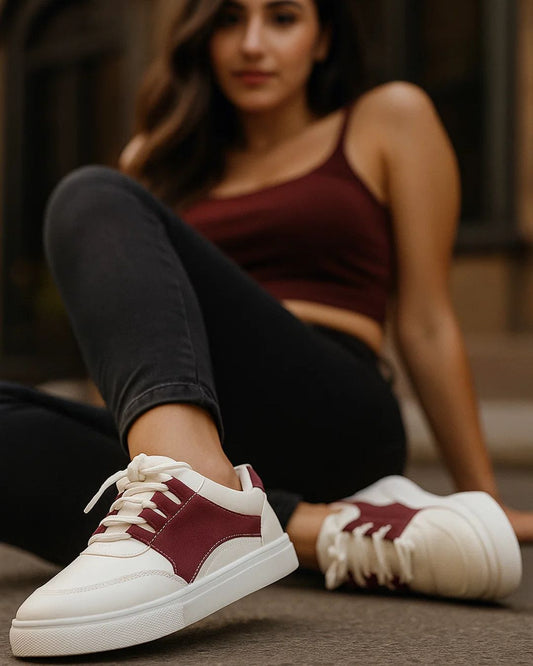 Person wearing maroon and white sneakers sitting on a surface.