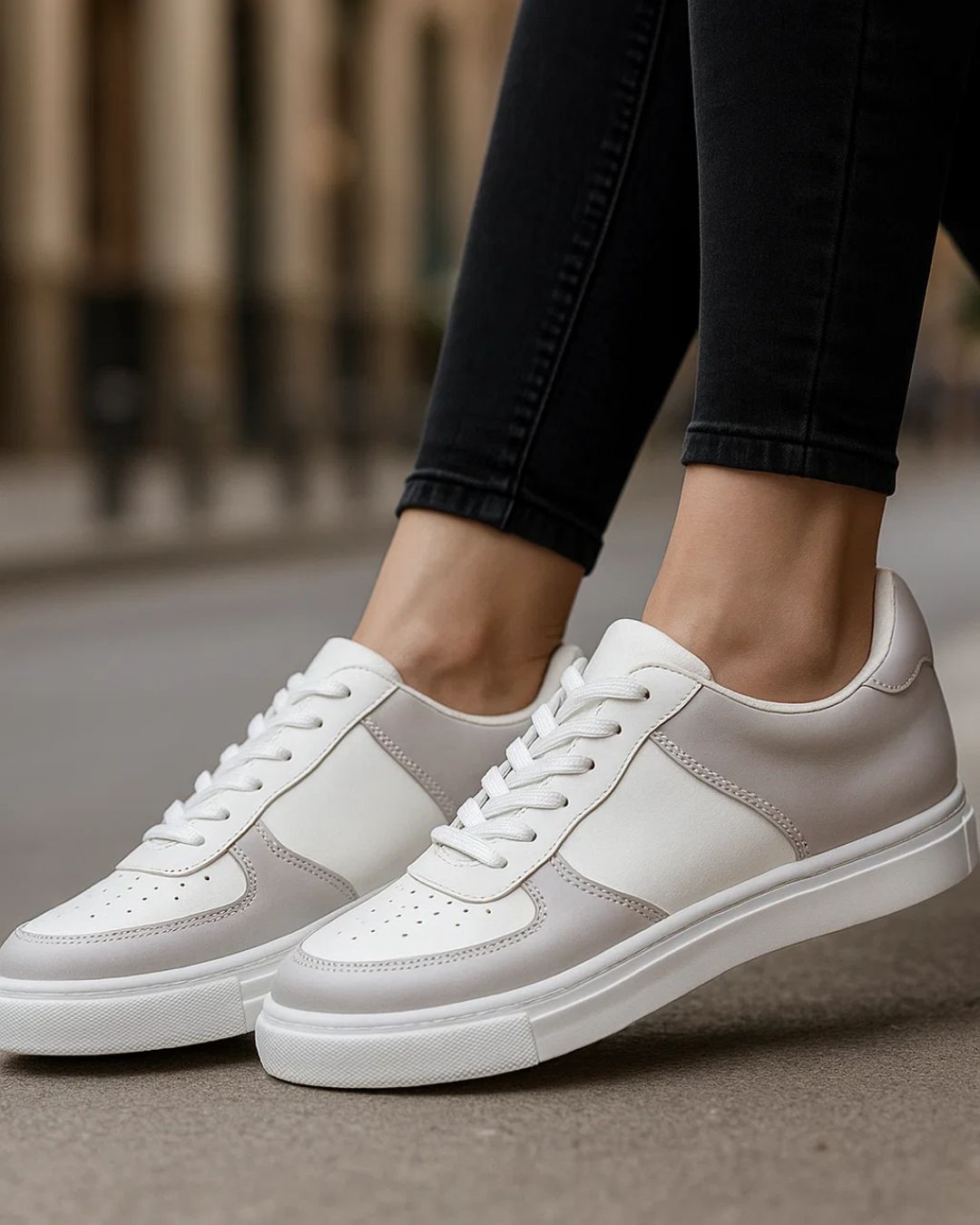 White sneakers worn with black pants on a blurred background