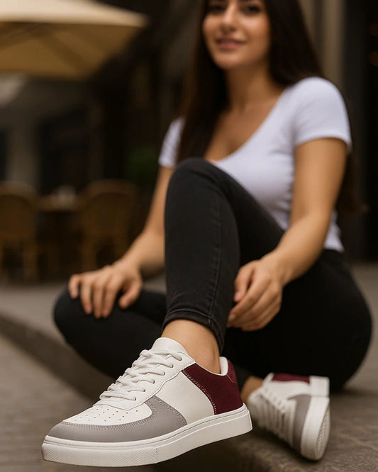 Person wearing white and burgundy sneakers sitting on the floor.