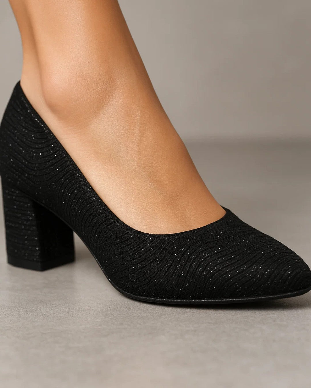 Black textured high-heeled shoe on a neutral background