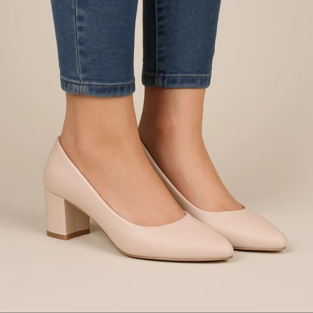 Beige high-heeled shoes worn with blue jeans on a neutral background