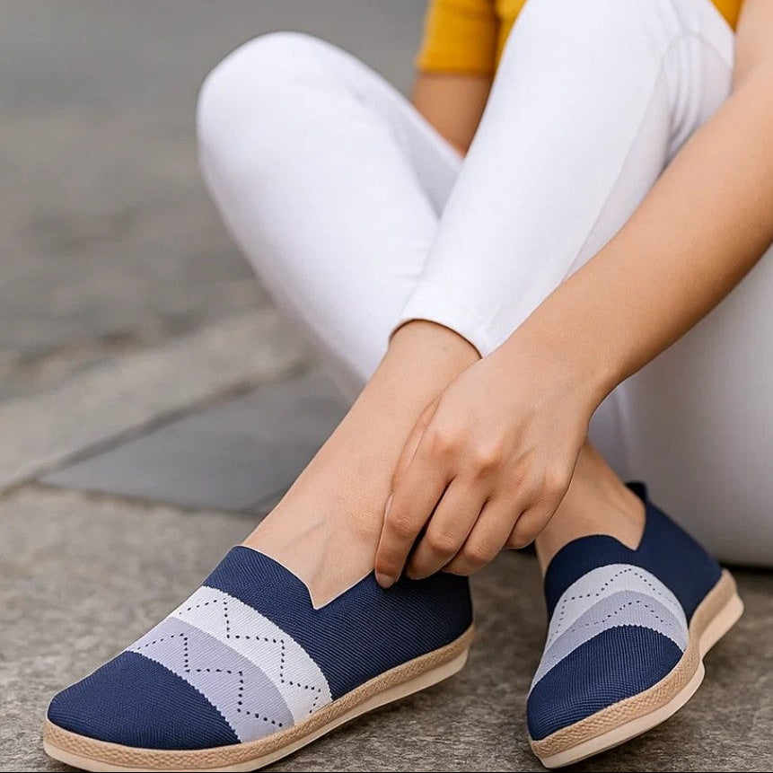 Woman wearing navy and white shoes sitting on a stone step.