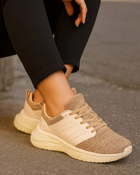 Beige running shoes worn with black pants on a blurred background