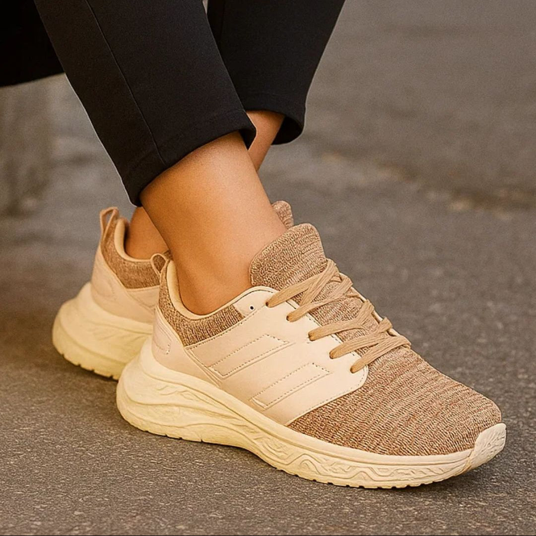 Beige running shoes worn with black pants on a neutral background