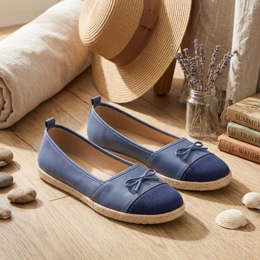 Blue flat shoes with bow details on a wooden floor with a hat and books in the background.